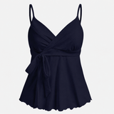 Sleeveless wrap-front peplum cami top with spaghetti straps and adjustable waist tie, styled for elegant everyday wear