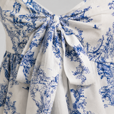 Sleeveless peplum cami top with sweetheart neckline, front bow tie detail, and flared hem in a toile-inspired print