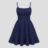 Sleeveless mini sundress with square neckline, smocked waistband, textured fabric, and flared ruffle hem
